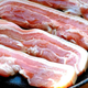 Raw bacon cooking in a cast-iron pan